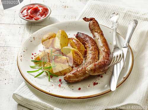 Image of grilled sausages and potatoes on white wooden table