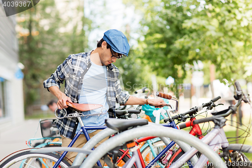 Image of hipster man parking fixed gear bike on city street