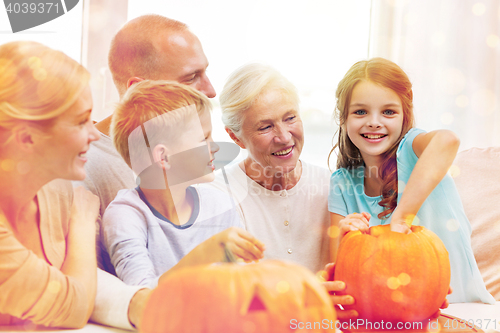 Image of happy family sitting with pumpkins at home