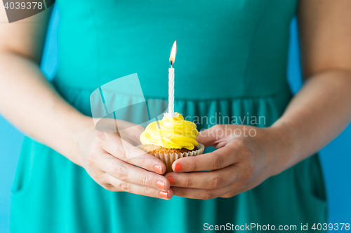 Image of woman with burning candle on birthday cupcake