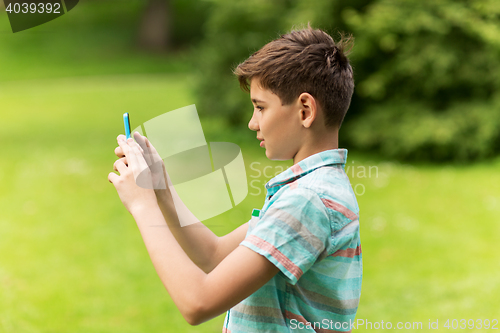 Image of boy with smartphone playing game in summer park