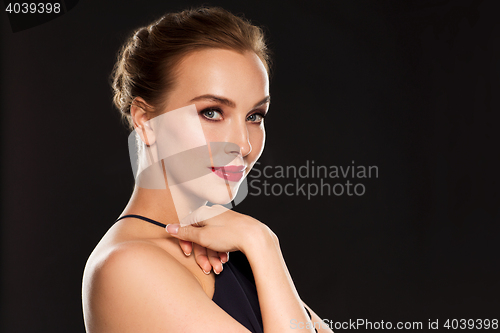 Image of beautiful woman in black over dark background