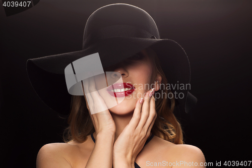 Image of beautiful woman in black hat over dark background