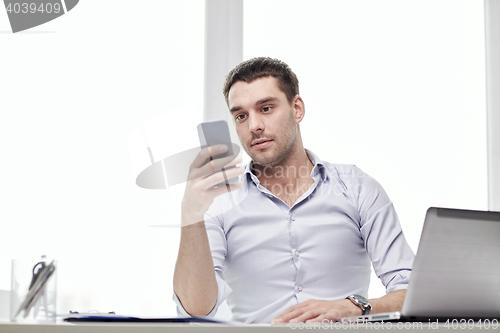 Image of businessman with smartphone and laptop at office