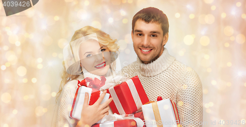 Image of happy couple in sweaters holding christmas gifts 