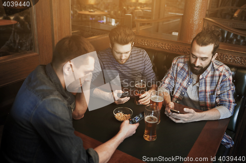 Image of men with smartphones drinking beer at bar or pub