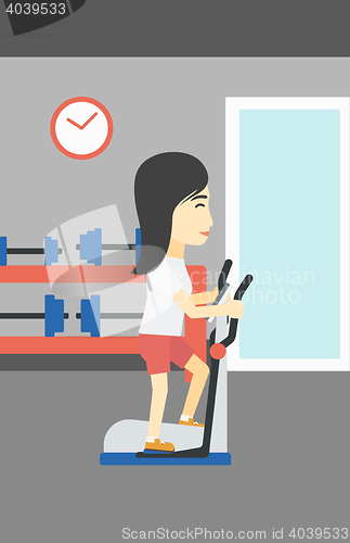 Image of Woman exercising on elliptical trainer.
