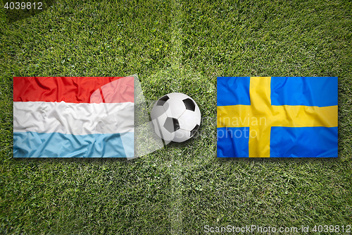 Image of Luxembourg and Sweden flags on soccer field