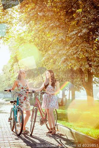 Image of The two young girls with bicycles in park