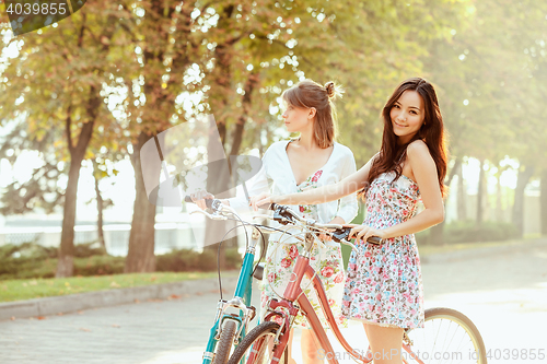 Image of The two young girls with bicycles in park