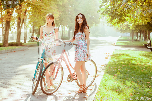 Image of The two young girls with bicycles in park