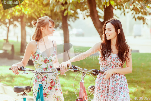 Image of The two young girls with bicycles in park