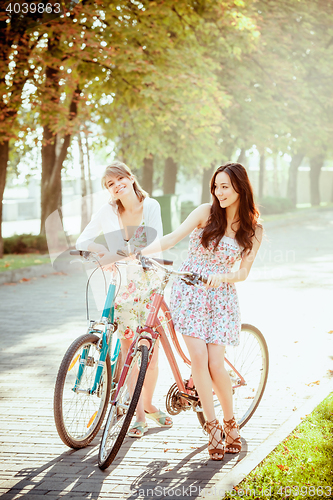 Image of The two young girls with bicycles in park