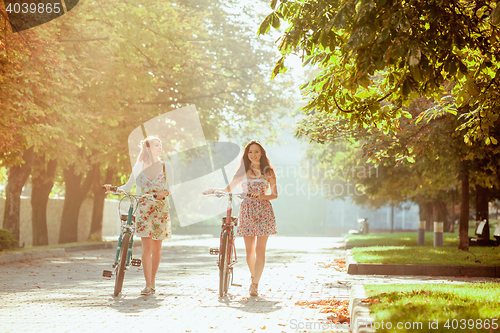 Image of The two young girls with bicycles in park