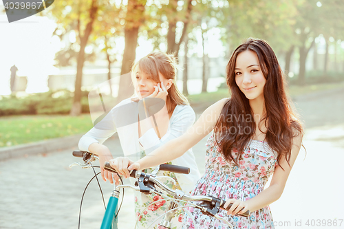 Image of The two young girls with bicycles in park