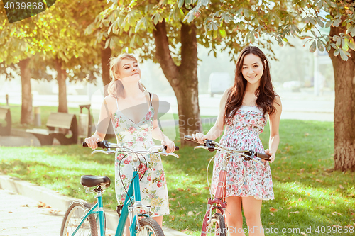 Image of The two young girls with bicycles in park