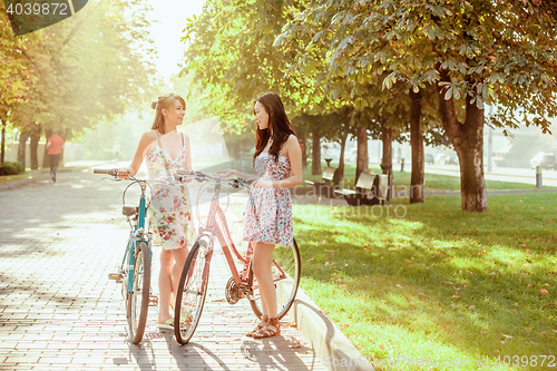 Image of The two young girls with bicycles in park