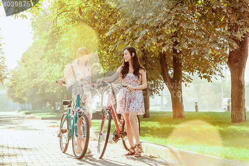 Image of The two young girls with bicycles in park