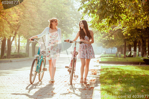 Image of The two young girls with bicycles in park