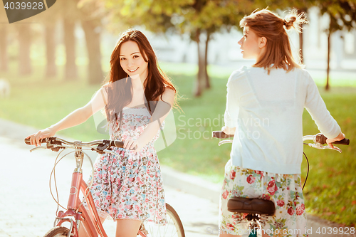 Image of The two young girls with bicycles in park
