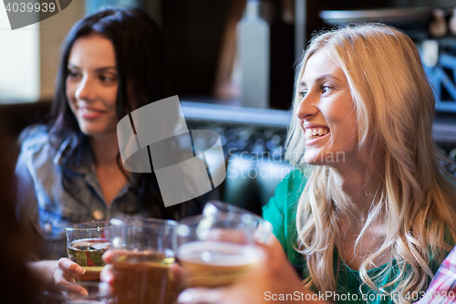 Image of happy female friends drinking beer at bar or pub