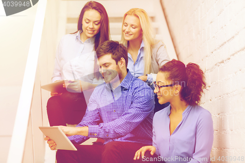 Image of team with tablet pc computer sitting on staircase