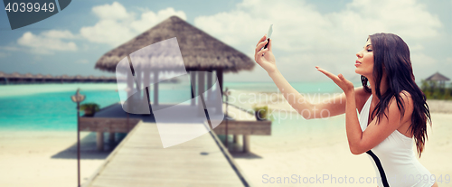 Image of young woman taking selfie with smartphone