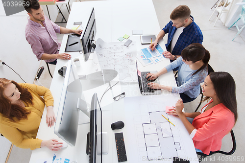 Image of creative team with computers, blueprint at office