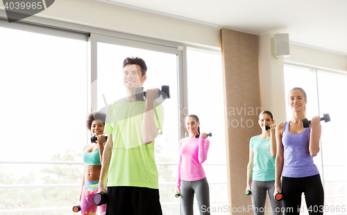 Image of group of smiling people exercising with dumbbells