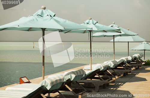 Image of parasol and sunbeds by sea on maldives beach