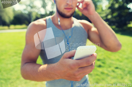 Image of young man with earphones and smartphone at park