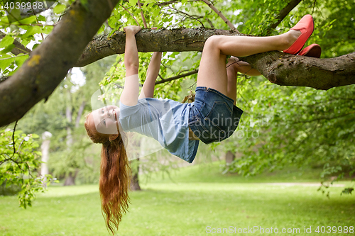 Image of happy little girl hanging on tree in summer park