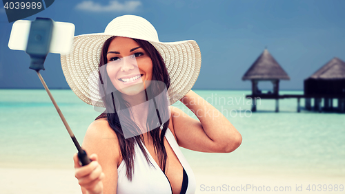 Image of smiling young woman taking selfie with smartphone