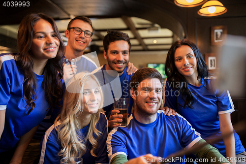 Image of football fans with beer taking selfie at pub