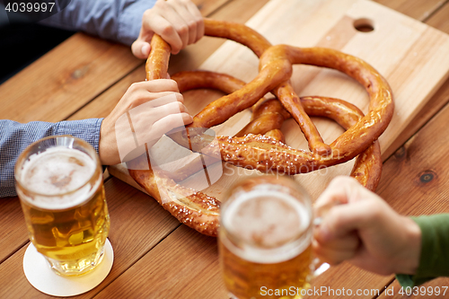 Image of close up of men drinking beer with pretzels at pub