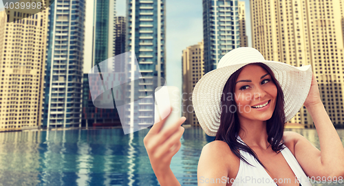 Image of young woman taking selfie with smartphone