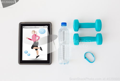 Image of tablet pc, dumbbells, fitness tracker and bottle