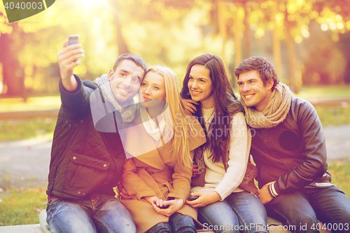 Image of group of friends with photo camera in autumn park