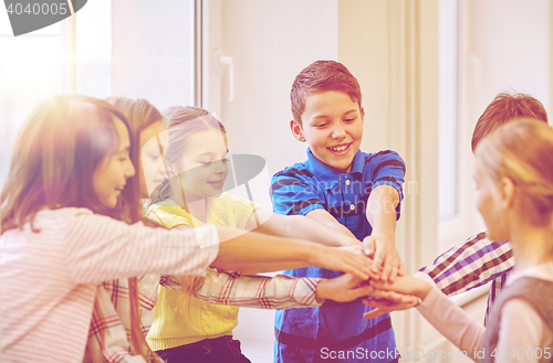 Image of group of smiling school kids putting hands on top