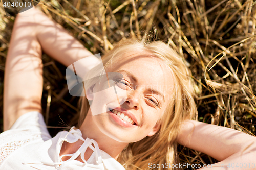 Image of happy young woman lying on cereal field