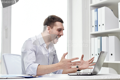 Image of angry businessman with laptop and papers in office