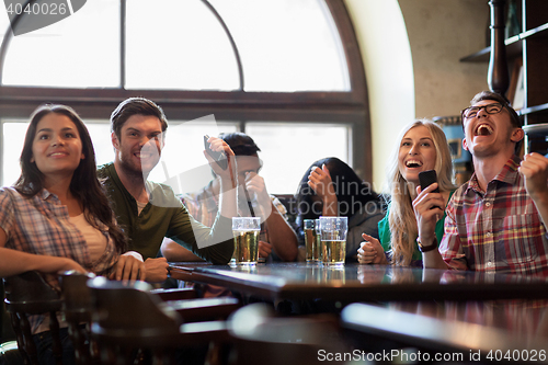 Image of friends with beer watching football at bar or pub