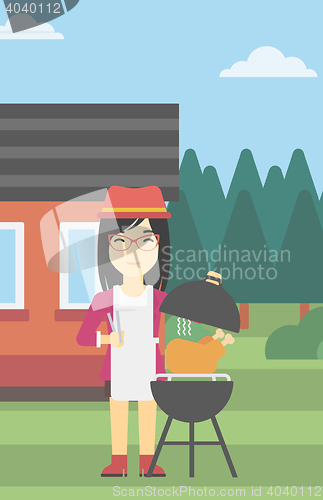 Image of Woman cooking chicken on barbecue grill.