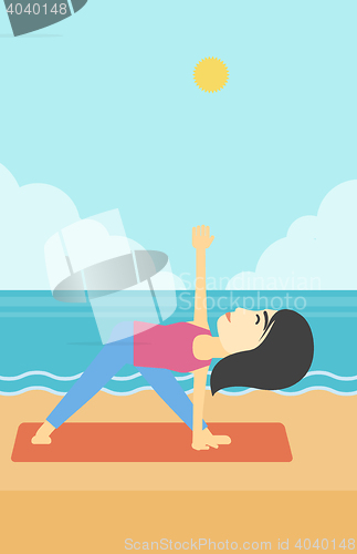 Image of Woman practicing yoga triangle pose on the beach.