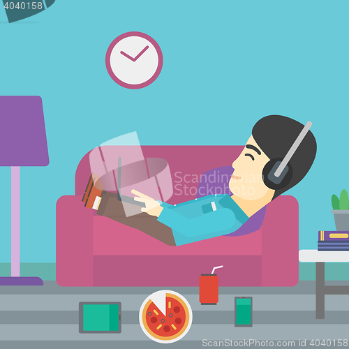 Image of Man lying on sofa with many gadgets.