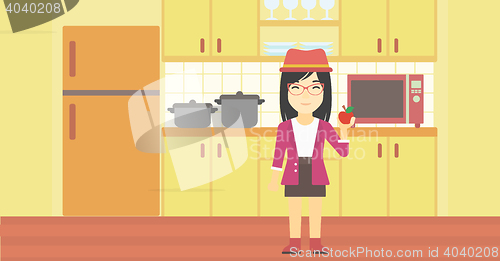 Image of Young woman with apple in the kitchen.