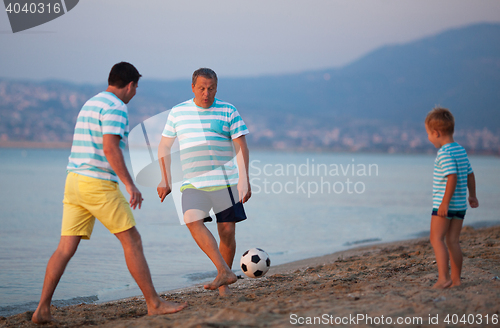 Image of Family team of three playing football at the seaside