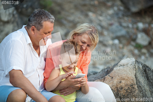 Image of Happy boy with cell phone and grandparents outdoor