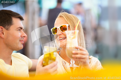 Image of Happy couple drinking cocktails outdoor