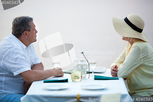 Image of Side view of adult couple sitting at table with wine